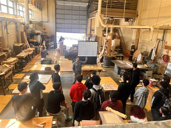 Students gather round a Universal Technical Institute representative to hear about career path options for their future.